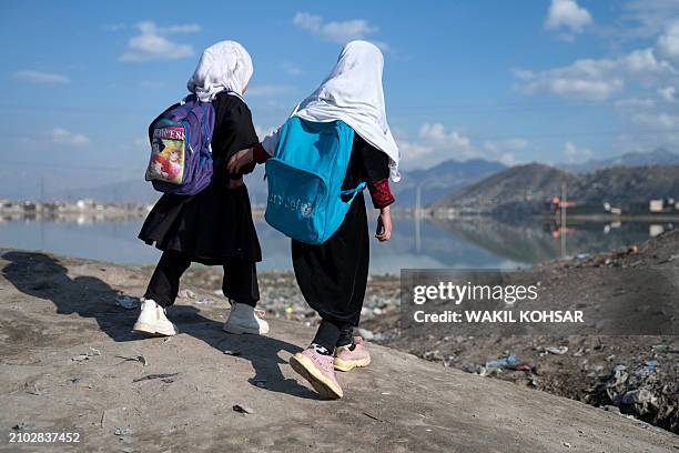 Afghan primary school girls make their way to home near the Shuhada lake in Kabul on March 24, 2024.