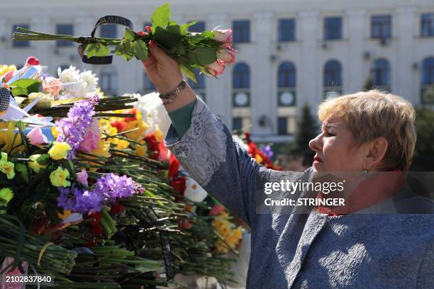 Woman lays flowers at a makeshift memorial in Simferopol, Crimea, on March 24 as Russia observes a national day of mourning after a massacre in the...