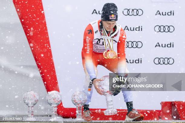 Switzerland's Marco Odermatt places his trophy globes on the podium after winning the overall season title of the Men's FIS Alpine Skiing World Cup,...