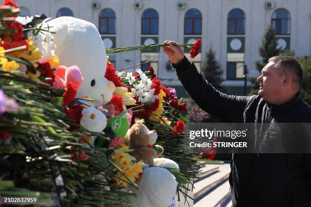 Man lays flowers at a makeshift memorial in Simferopol, Crimea, on March 24 as Russia observes a national day of mourning after a massacre in the...