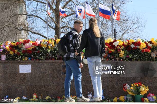 Couple visits a makeshift memorial in Simferopol, Crimea, on March 24 as Russia observes a national day of mourning after a massacre in the Crocus...