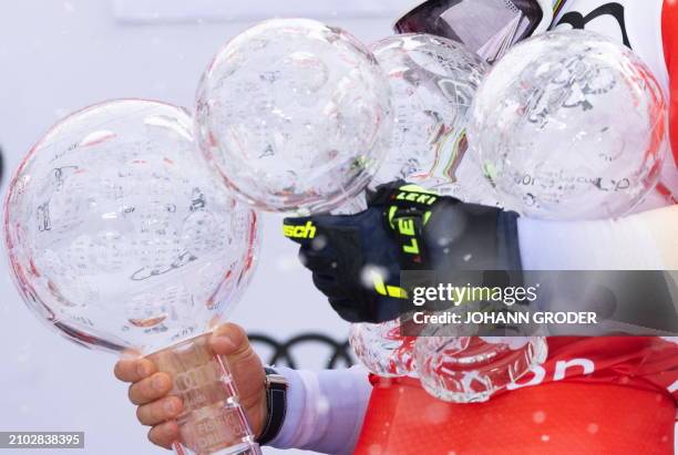 Switzerland's Marco Odermatt holds his trophy globes as he celebrates on the podium after winning the overall season title of the Men's FIS Alpine...