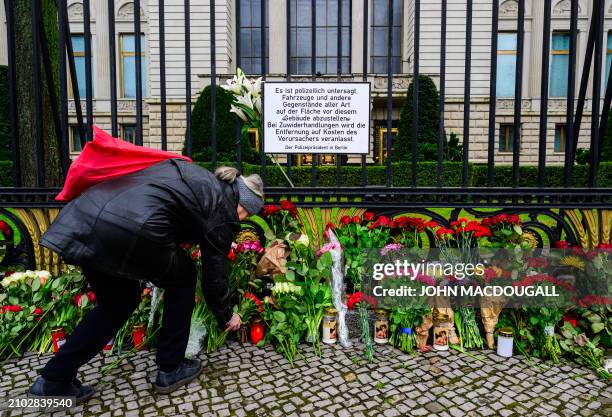 Woman lays flowers at an improvised memorial outside the Russian embassy in Berlin on March 24 two days after a gun attack in Krasnogorsk, outside...