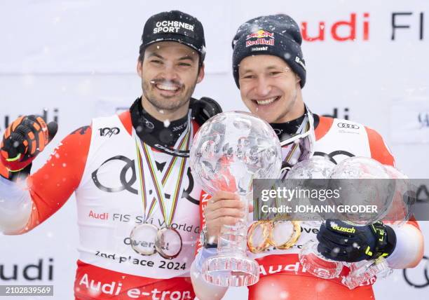 Switzerland's Marco Odermatt holds his trophies as he celebrates on the podium after winning the overall season title of the Men's FIS Alpine Skiing...