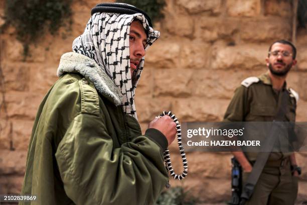 An Israeli settler dressed in Arab garb and wearing a Palestinian keffiyeh headdress as a Purim costume walks along Al-Shuhada street, which is...