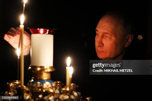 In this pool photograph distributed by the Russian state agency Sputnik, Russia's President Vladimir Putin lights a candle during his visit to a...