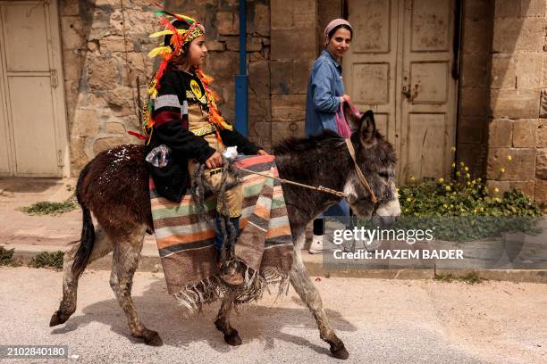 Girl wearing Native American costume rides a mule colt along Al-Shuhada street, which is largely closed to Palestinians, in the divided city of...