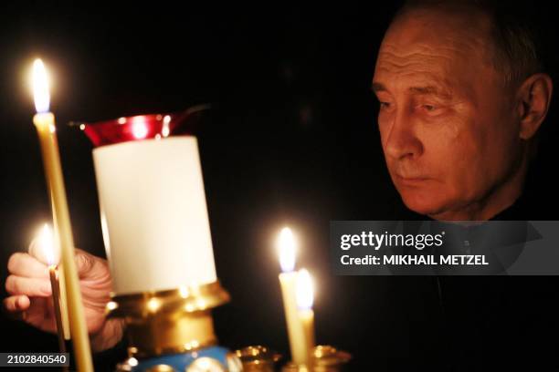 In this pool photograph distributed by the Russian state agency Sputnik, Russia's President Vladimir Putin lights a candle during his visit to a...