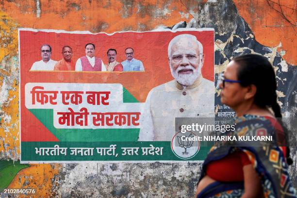 Woman walks past an election campaign poster of the Bharatiya Janata Party featuring their leader and India's Prime Minister Narendra Modi , along a...