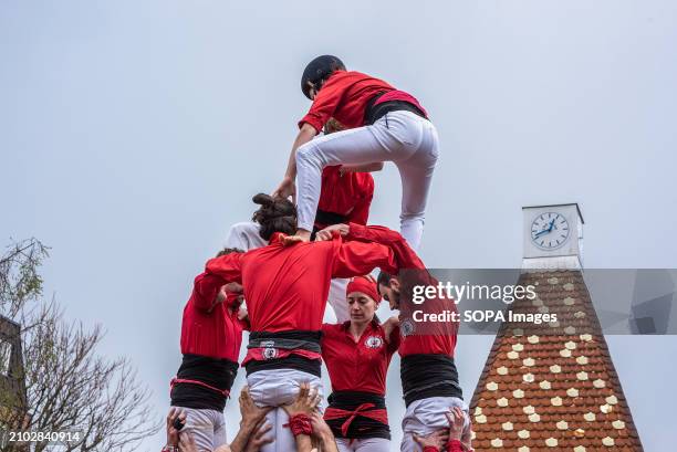 Two performers climb on the top of the others during the performance. Castell means in Catalan literally castle. Castellers are those people who...
