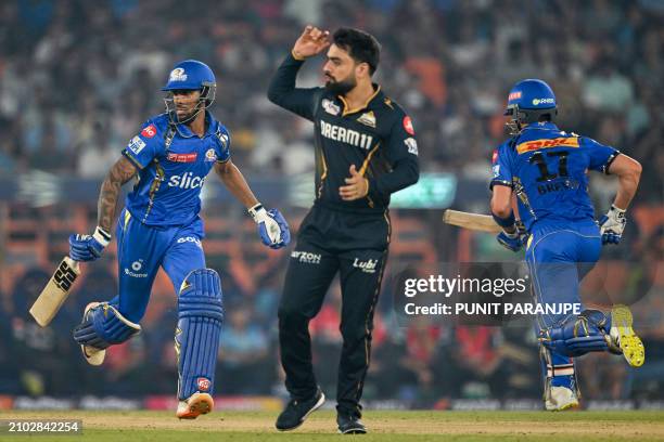 Mumbai Indians' Tilak Varma and Dewald Brevis run between the wickets as Gujarat Titans' Rashid Khan looks on during the Indian Premier League...