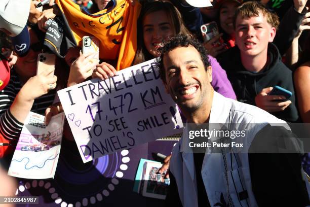 Daniel Ricciardo of Australia and Visa Cash App RB poses for a photo with a fan holding a banner on the Melbourne Walk prior to practice ahead of the...