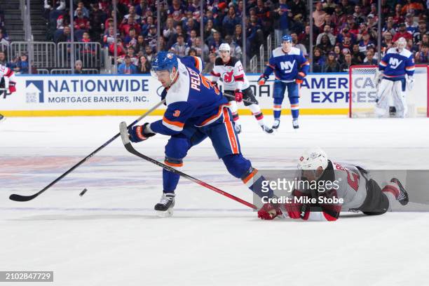 Adam Pelech of the New York Islanders beats Jesper Bratt of the New Jersey Devils to puck at UBS Arena on March 24, 2024 in Elmont, New York.