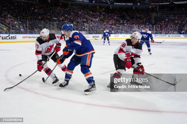 Jean-Gabriel Pageau of the New York Islanders races to puck against Nick DeSimone and Erik Haula of the New Jersey Devils at UBS Arena on March 24,...