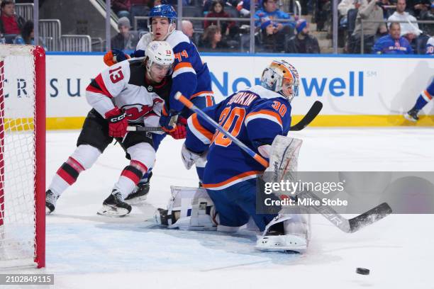 Ilya Sorokin and Jean-Gabriel Pageau of the New York Islanders defend shot on goal by Nico Hischier of the New Jersey Devils at UBS Arena on March...