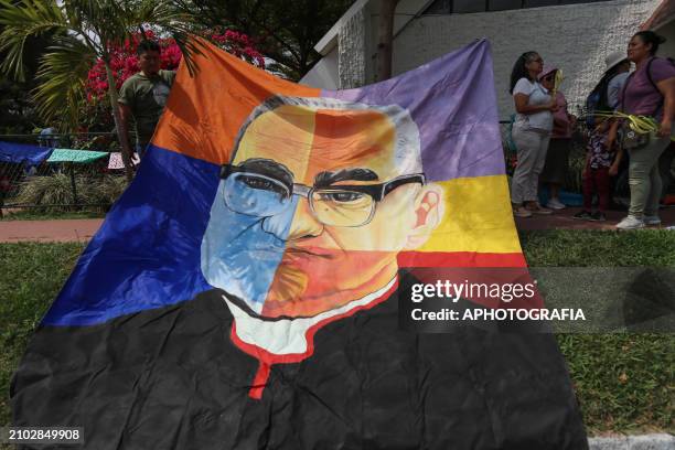 People carry a giant banner with an art of Romero's face during the commemoration activities of the 44th anniversary of the assassination of...