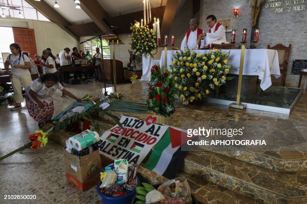 Woman leaves an offering on the altar of a church next to a banner in support of Palestine while participating in a mass during the commemoration...