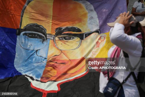 People carry a giant banner with an art of Romero's face during the commemoration activities of the 44th anniversary of the assassination of...