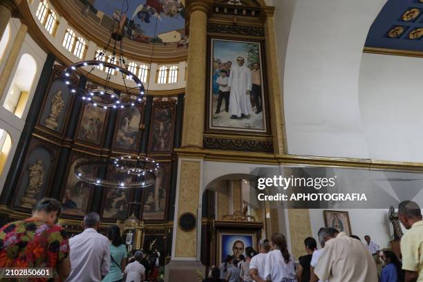 People stand in front of a portrait of Romero at a mass during the commemoration activities of the 44th anniversary of the assassination of...