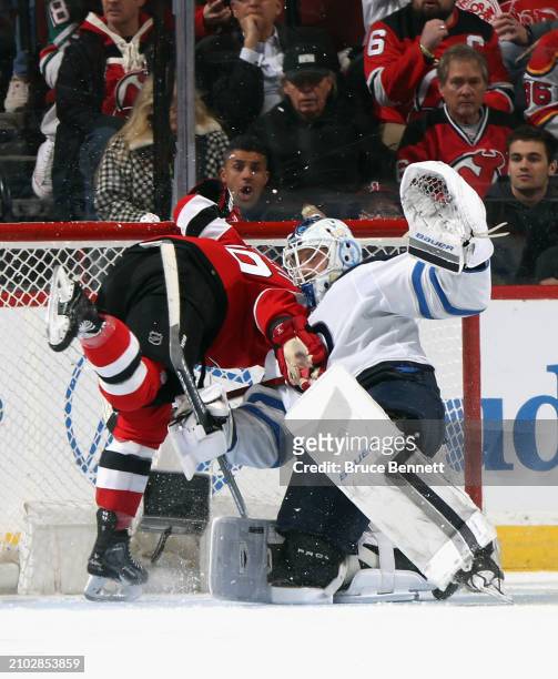 Ondrej Palat of the New Jersey Devils crashes into Laurent Brossoit of the Winnipeg Jets during the first period at Prudential Center on March 21,...
