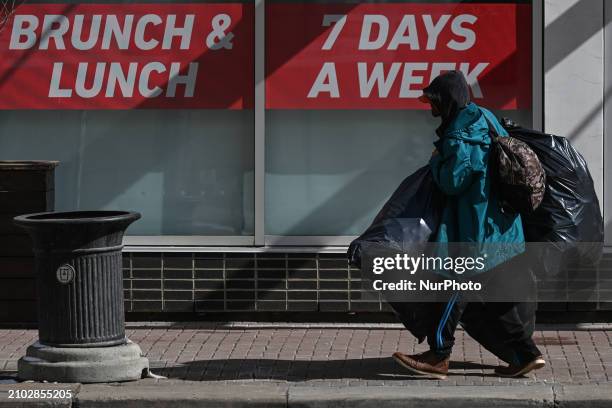 Homeless man carrying bags walks on the street in the downtown area of Edmonton, on March 24 in Edmonton, Alberta, Canada.