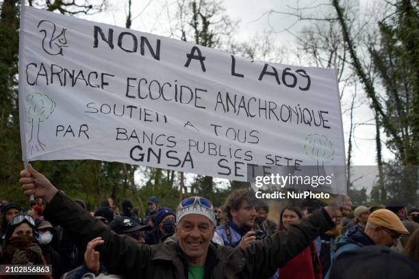 Man is holding a banner that reads 'No to the A69, ecocidal anachronic slaughter'. After spending 37 days in the trees, the last three 'Ecureuils' ,...