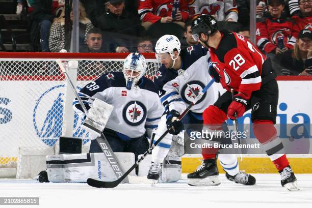 Laurent Brossoit and Colin Miller of the Winnipeg Jets defend against Timo Meier of the New Jersey Devils during the first period at Prudential...