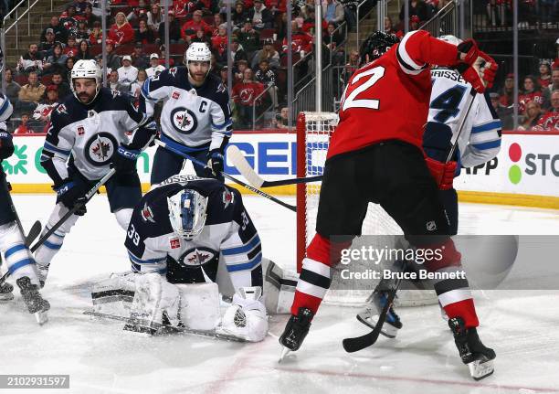 Laurent Brossoit of the Winnipeg Jets covers the puck during the second period against the New Jersey Devils at Prudential Center on March 21, 2024...