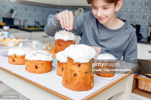 a boy decorating an easter cake in a kitchen - maundy thursday stock pictures, royalty-free photos & images