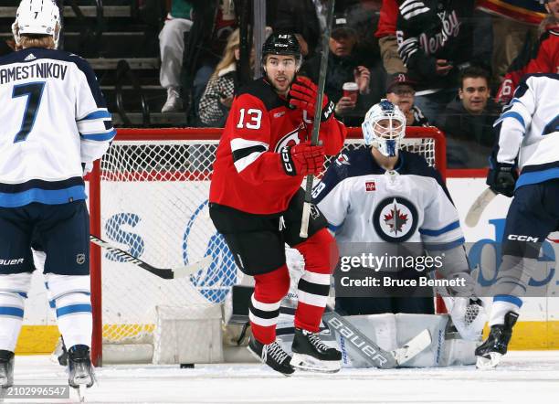 Nico Hischier of the New Jersey Devils celebrates a third period goal by Jack Hughes against Laurent Brossoit of the Winnipeg Jets at Prudential...