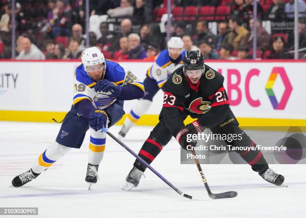 Pavel Buchnevich of the St. Louis Blues pokes the puck away while battling with Travis Hamonic of the Ottawa Senators during the third period at...