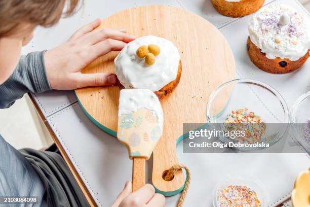 boy decorating easter cakes with sugar icing - osterkuchen stock-fotos und bilder