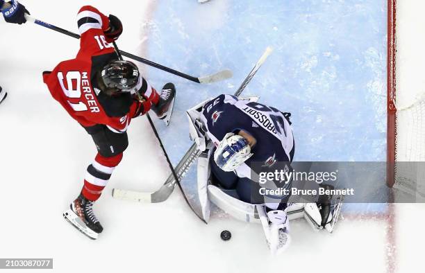 Laurent Brossoit of the Winnipeg Jets makes the save on Dawson Mercer of the New Jersey Devils at Prudential Center on March 21, 2024 in Newark, New...