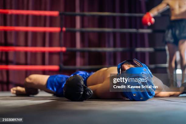 caucasian professional sport young man loser exercise in fitness club. attractive athlete in sportswear and boxing gloves fainting and falling on the ground after competitor punching in gym stadium. - abs miss fotografías e imágenes de stock