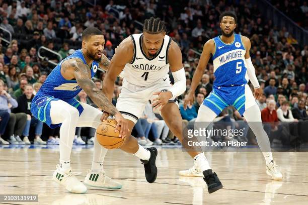 Damian Lillard of the Milwaukee Bucks steals the dribble from Dennis Smith Jr. #4 of the Brooklyn Nets during the second half of the game at Fiserv...