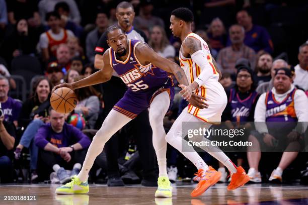 Kevin Durant of the Phoenix Suns posts up on Dejounte Murray of the Atlanta Hawks during the first half at Footprint Center on March 21, 2024 in...