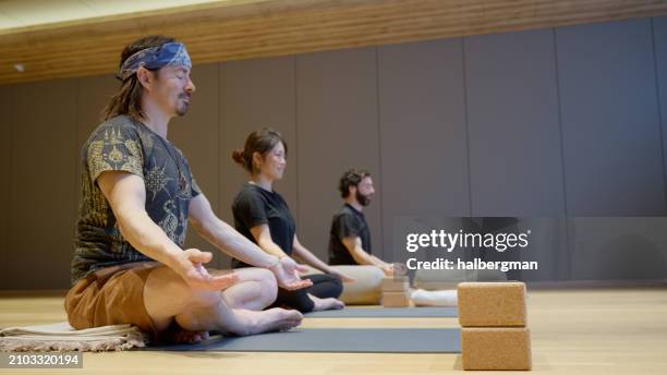 students meditating during yoga class in niseko, japan - yoga block stock pictures, royalty-free photos & images