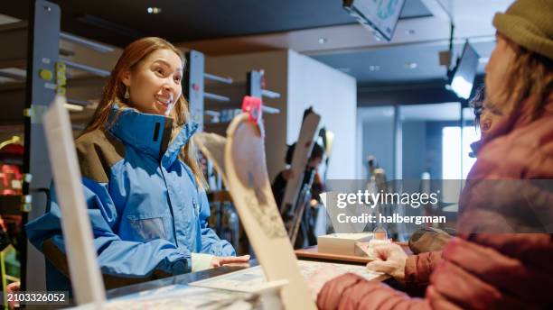 empleado animado de alquiler de esquís hablando con los clientes - turismo responsable fotografías e imágenes de stock