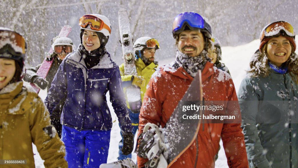 Smiling Friends Walking Through Heavy Snow at Night in Niseko