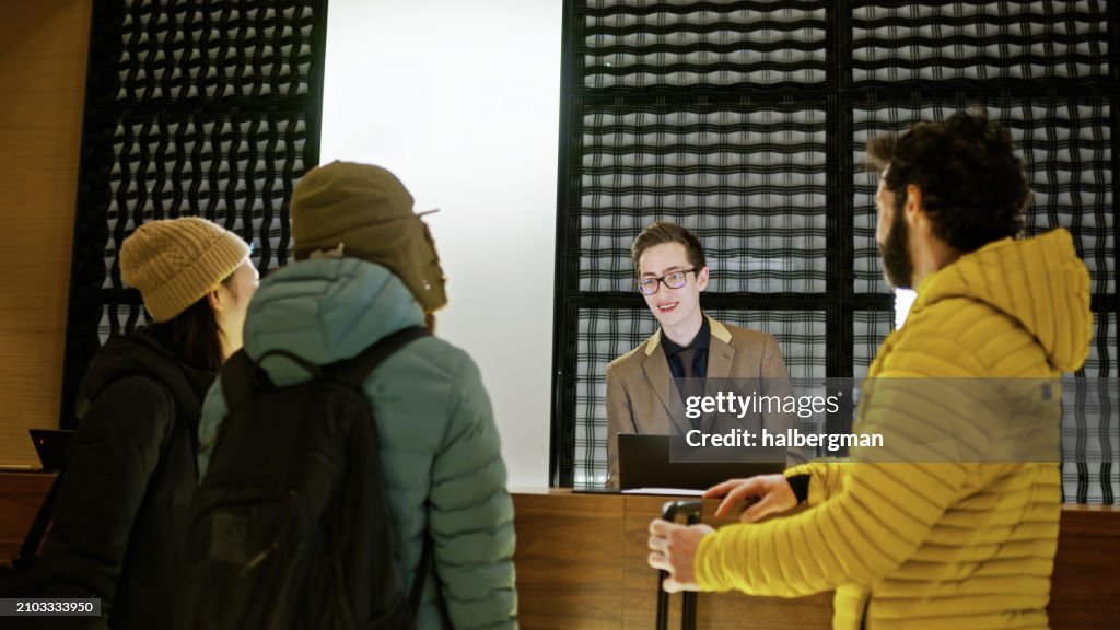 Young Receptionist Talking to Three Skiing Friends inside Niseko Hotel