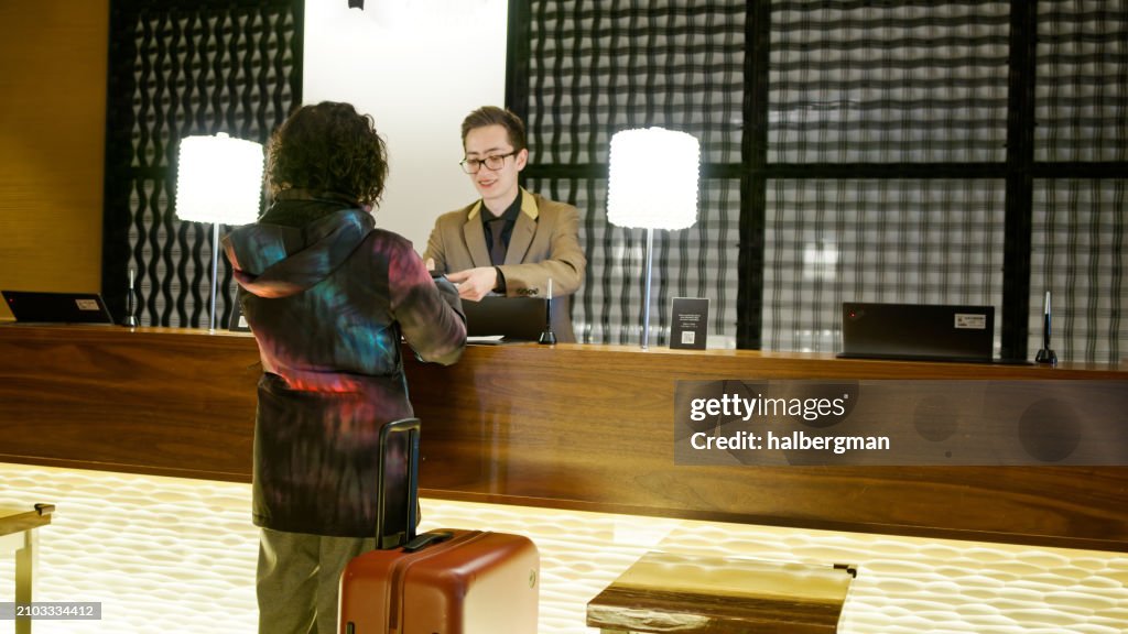 Solo Japanese Traveler in front of Reception Desk inside Niseko Hotel