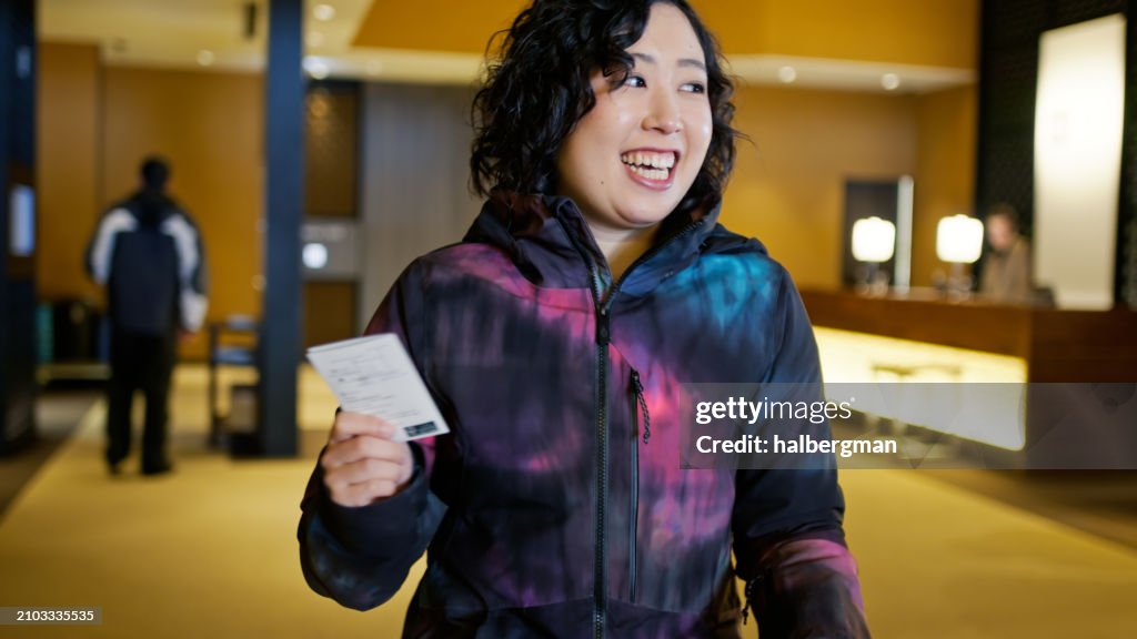 Jovial Japanese Woman Smiling with Keycard in Hand inside Niseko Hotel