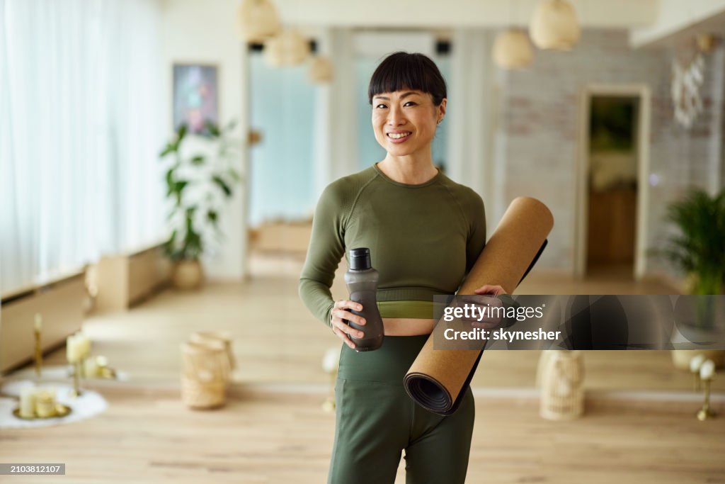 Mujer asiática feliz lista para la clase de yoga en un club de salud.