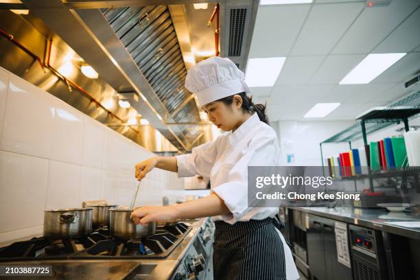asian female chef cooking in kitchen. - school cafeteria kitchen stock pictures, royalty-free photos & images