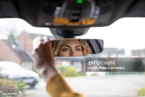 woman adjusting car rear view mirror - rear view mirror stock pictures, royalty-free photos & images