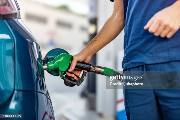 young man refuelling his modern car at petrol station - petrol tank stock pictures, royalty-free photos & images