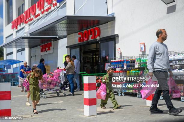 Children dressed as IDF soldiers carry groceries with their dad ahead of Shabbat and Purim on March 22, 2024 in Sderot, Israel. This is the first...