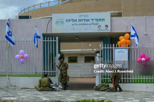 Soldiers guard outside a school while enjoying purim gift baskets on March 22, 2024 in Sderot, Israel. This is the first major Jewish holiday being...