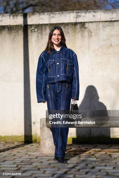 Belen Hostalet wears a navy blue denim pantsuit with white stitching, a black studded bag with a steel chain strap, outside Stella McCartney , during...