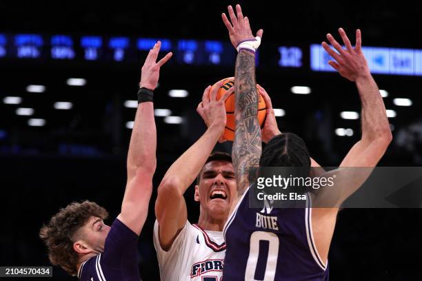 Nick Martinelli and Boo Buie of the Northwestern Wildcats defend Vladislav Goldin of the Florida Atlantic Owls i in the first round of the NCAA Men's...